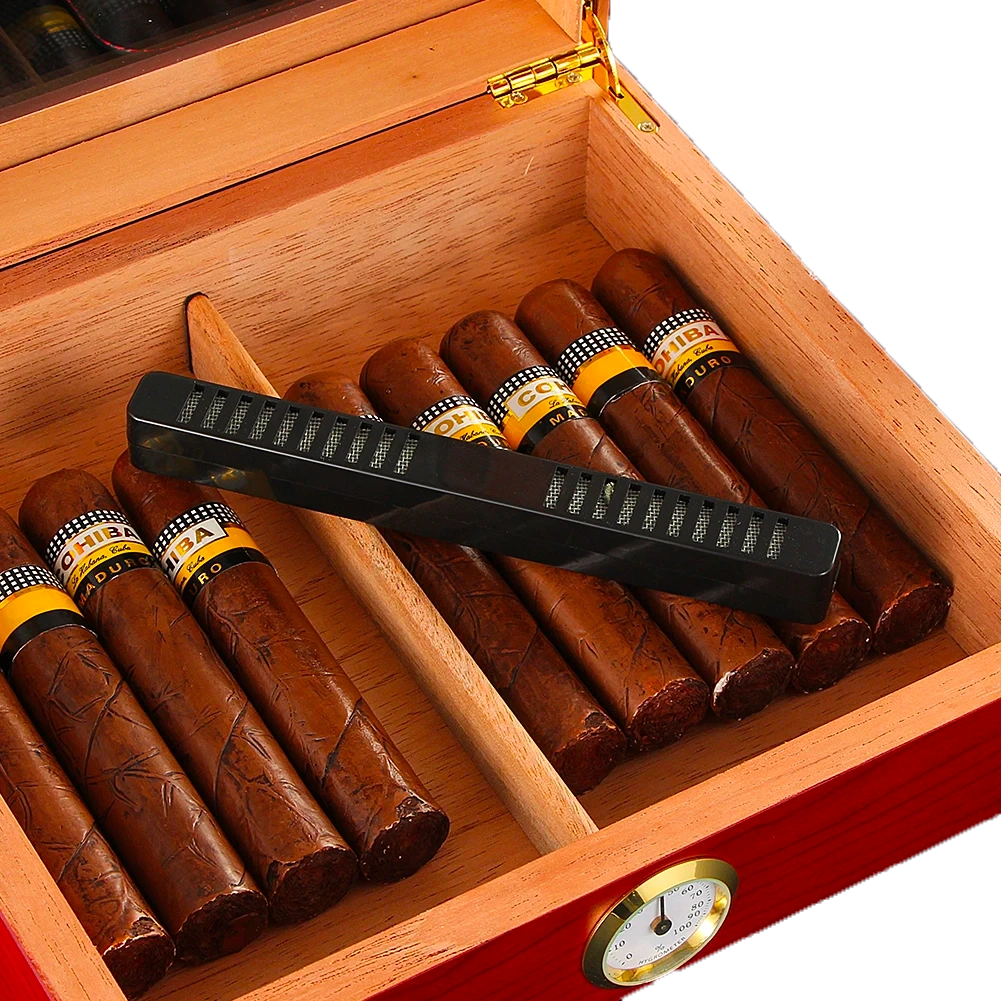 Humidor compact en bois de cèdre ouvert, avec un cigare à l'intérieur, montrant l'hygromètre et l'humidificateur pour une conservation optimale des cigares.